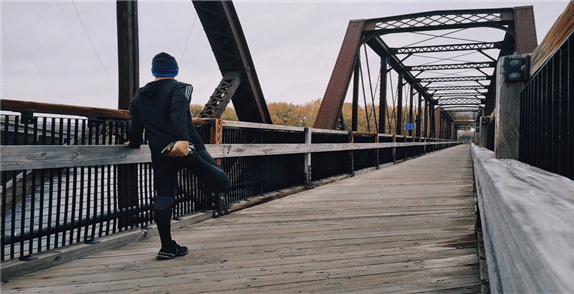 Jogger dehnt sich an der Brücke. Trading erfordert Fitness, physich und geistig