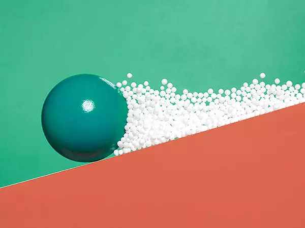 Large green sphere and lots of small white spheres on a red slope