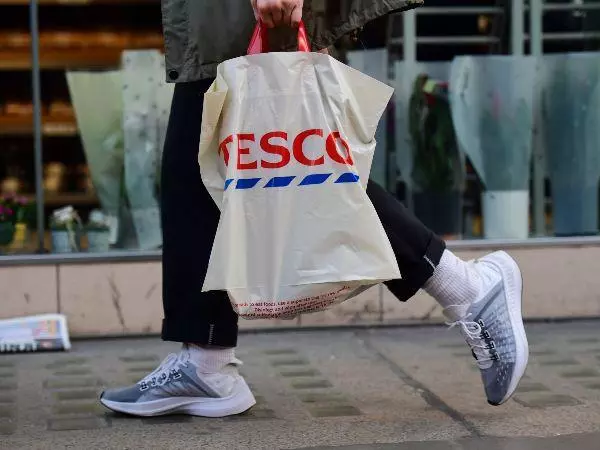 Person carrying Tesco bag