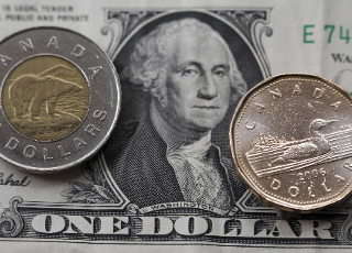 A two dollar Canadian "Tooney" coin and one dollar Canadian "Loonie" coin are arranged on the face of an American one dollar bill in Toronto, Ontario, on Tuesday, Sept. 25, 2007. Canada's dollar fell from near a 31-year high after Bank of Canada Governor David Dodge said the currency rose ``sharply above'' the central bank's assumed trading range.